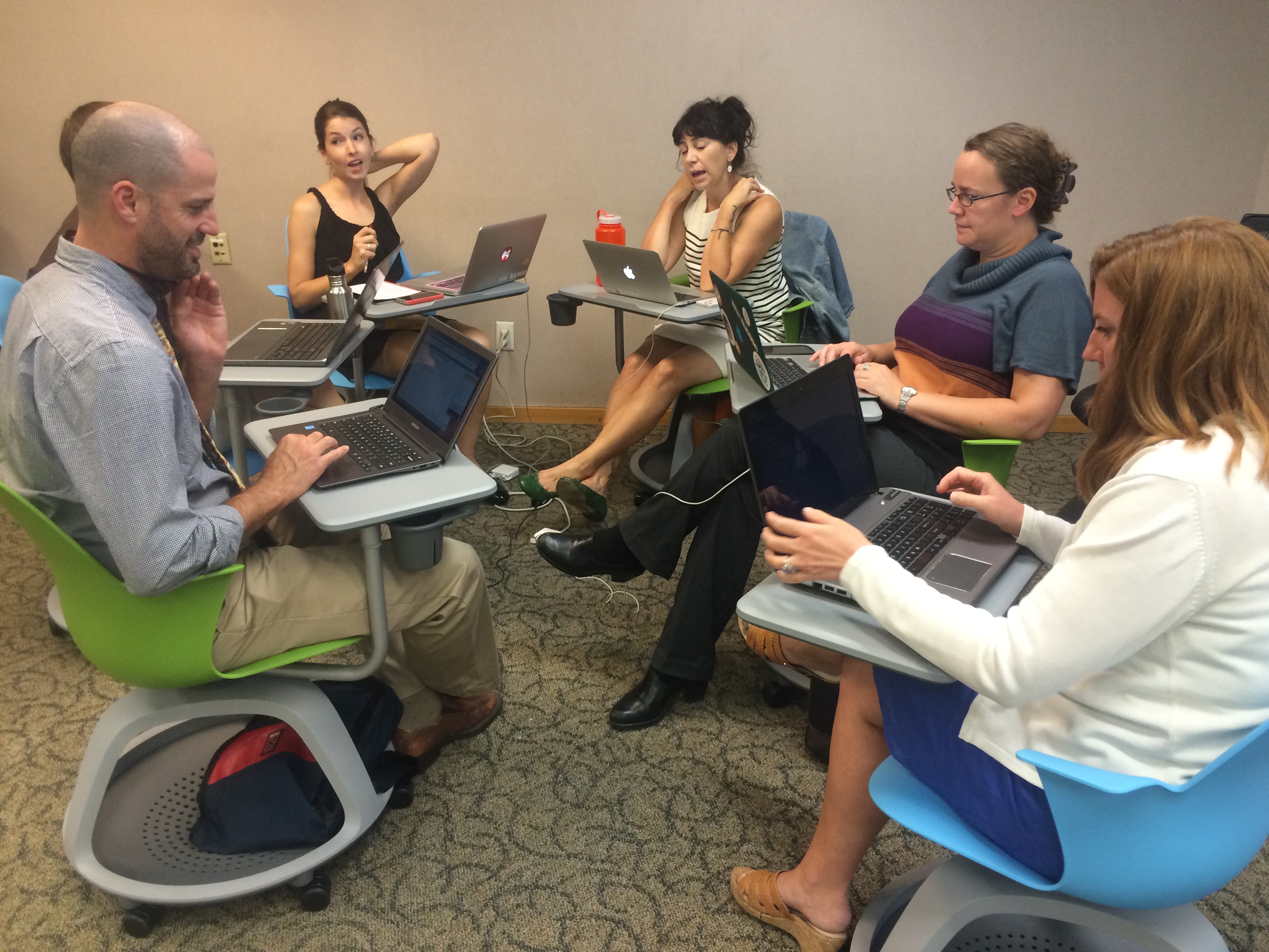 People sitting in circle using laptops